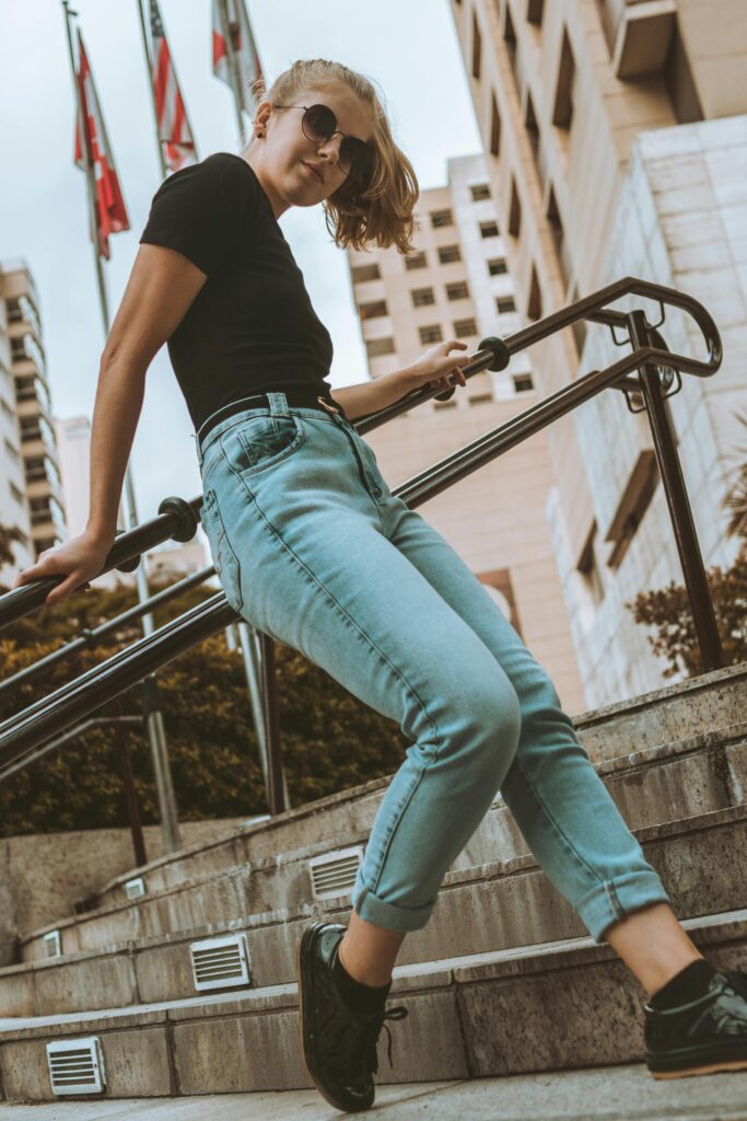 Young woman in casual attire posing on stairs in urban setting.