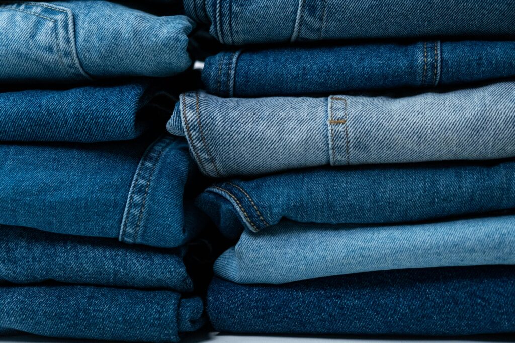 Close-up of stacked blue denim jeans showcasing different textures and shades.
